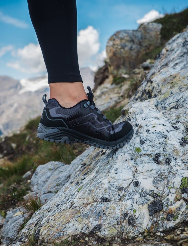 Trekingová bota na skále s horami v pozadí